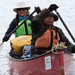 Two paddlers canoeing towards the camera in a fully equipped canoe
