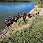 Sept canots avec des jeunes participants se préparant à quitter un campement sauvage le long du fleuve Yukon