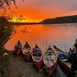 Canots vides attachés sur la rive du fleuve sous un coucher de soleil rouge
