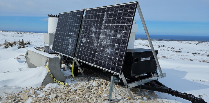 A solar panel unit is displayed outside on a clear day. It has damage to a number of panels on its surface.