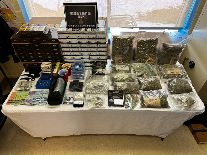 A number of items, including cash, contraband tobacco, weapons, scales, ammunition and various drugs, are displayed on a table in evidence bags.