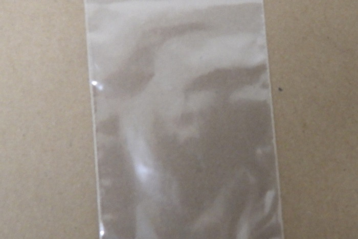 Two white triangular-shaped tablets are in a small clear sealed bag.